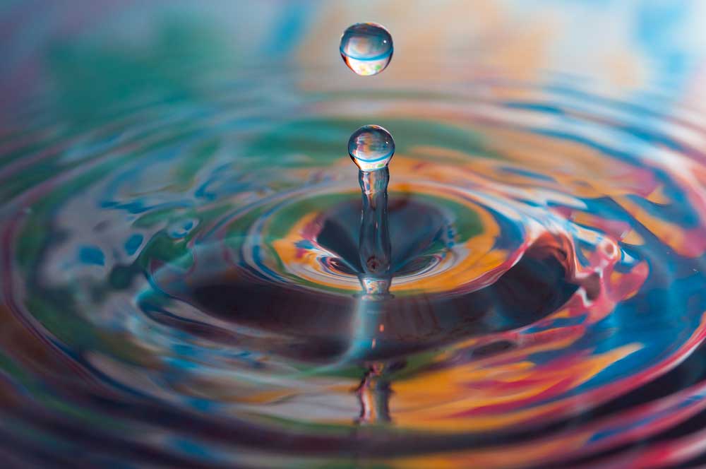 A macro photo of water drops falling into a pool of water